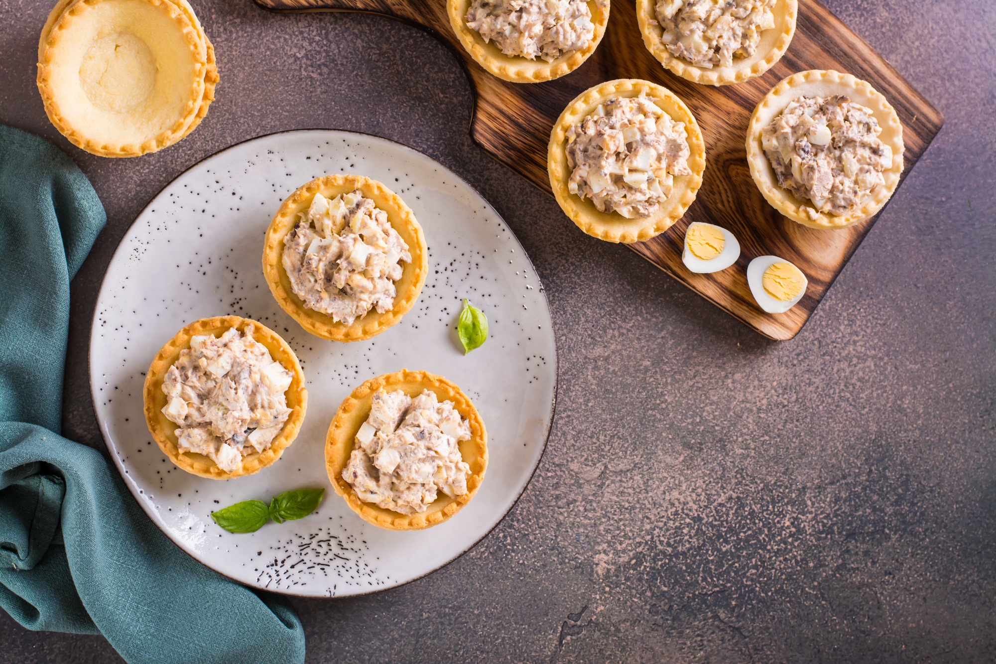 Appetizing tartlets with egg, canned tuna and onion salad on a plate on the table top view
